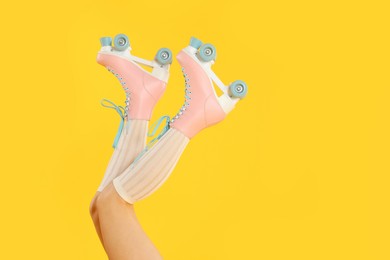 Photo of Woman in roller skates on orange background, closeup. Space for text