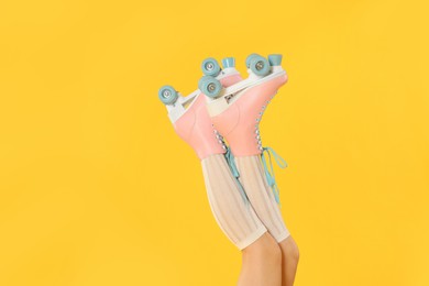 Photo of Woman in roller skates on orange background, closeup