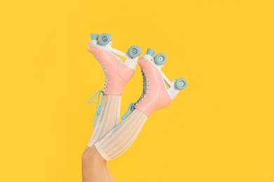 Photo of Woman in roller skates on orange background, closeup