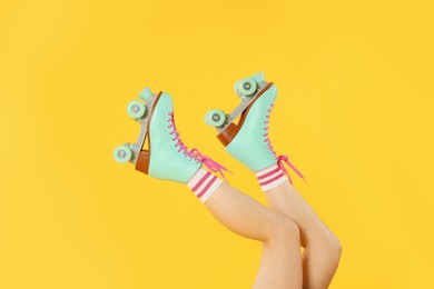 Photo of Woman in roller skates on orange background, closeup