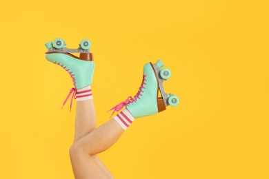 Photo of Woman in roller skates on orange background, closeup. Space for text