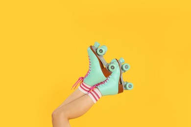 Photo of Woman in roller skates on orange background, closeup