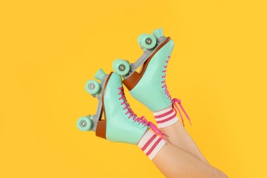 Photo of Woman in roller skates on orange background, closeup