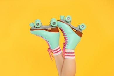 Photo of Woman in roller skates on orange background, closeup