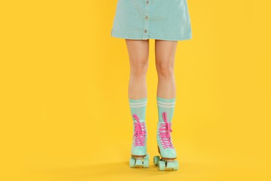 Photo of Woman in roller skates on orange background, closeup