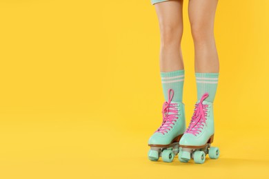 Photo of Woman in roller skates on orange background, closeup. Space for text