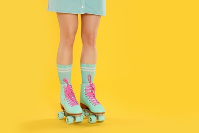 Photo of Woman in roller skates on orange background, closeup. Space for text