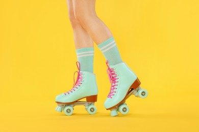 Photo of Woman in roller skates on orange background, closeup