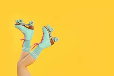 Photo of Woman in roller skates on orange background, closeup. Space for text