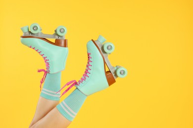 Photo of Woman in roller skates on orange background, closeup