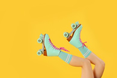 Photo of Woman in roller skates on orange background, closeup, space for text
