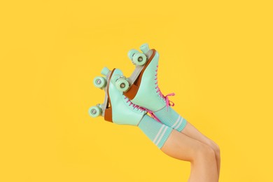 Photo of Woman in roller skates on orange background, closeup