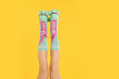 Photo of Woman in roller skates on orange background, closeup