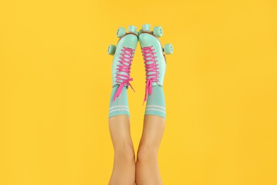 Photo of Woman in roller skates on orange background, closeup