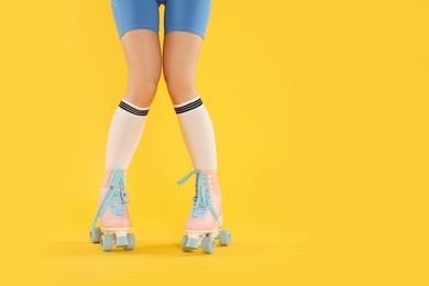 Photo of Woman in roller skates on orange background, closeup. Space for text
