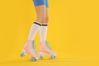 Photo of Woman in roller skates on orange background, closeup. Space for text