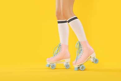 Photo of Woman in roller skates on orange background, closeup. Space for text