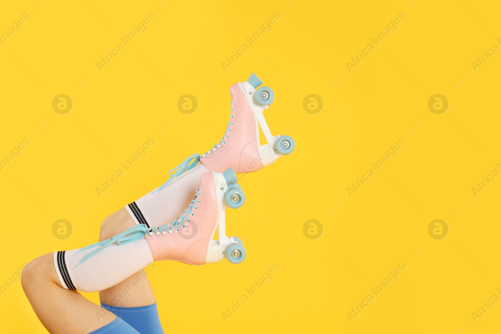 Photo of Woman in roller skates on orange background, closeup. Space for text