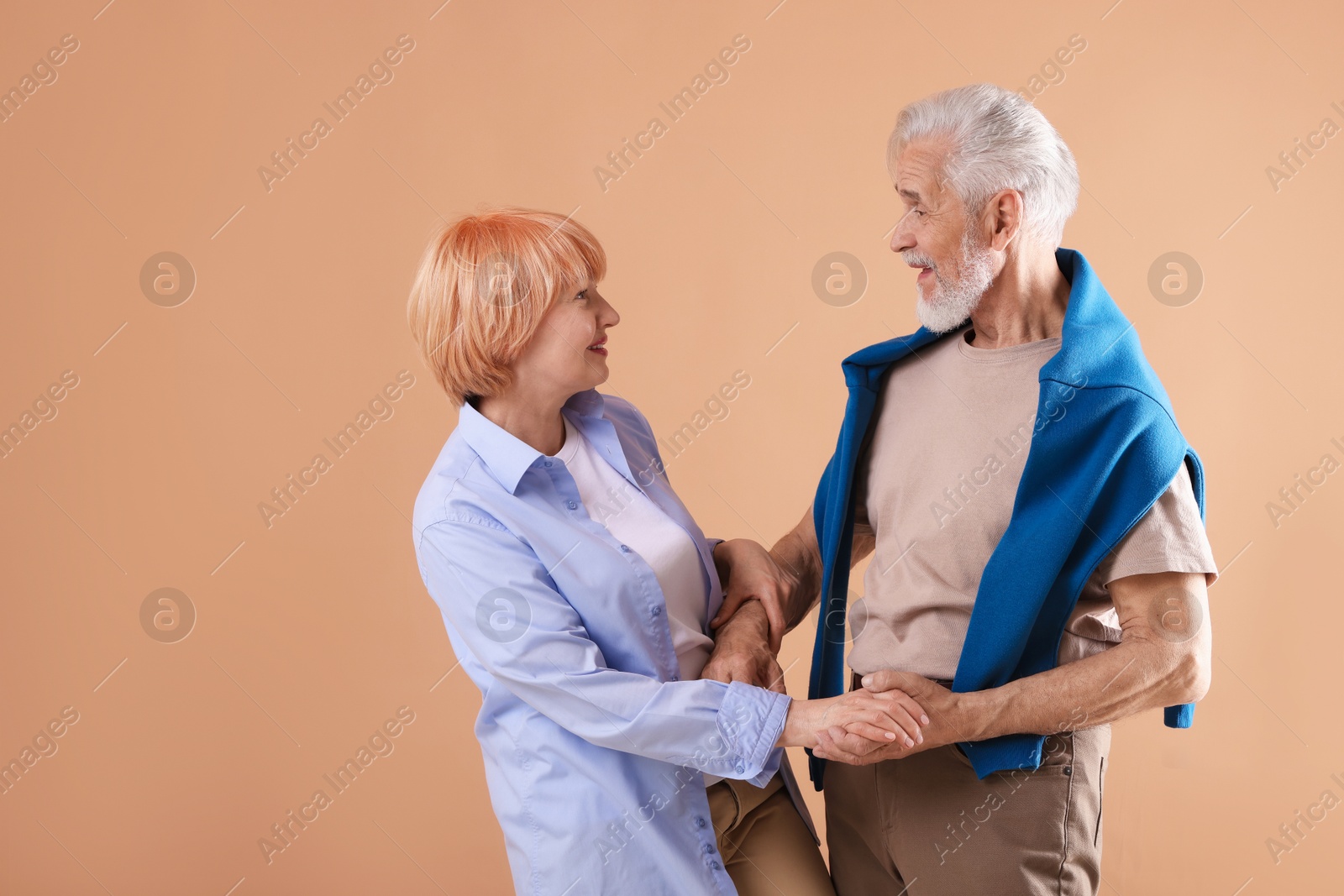 Lovely senior couple together on light brown background, space for text Photo of Lovely senior couple together on light brown background, space for text