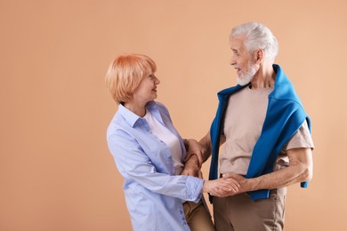 Photo of Lovely senior couple together on light brown background, space for text