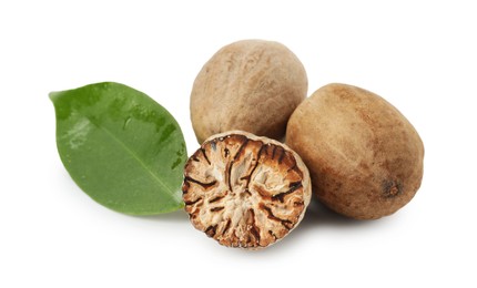 Photo of Whole, cut nutmegs and leaf isolated on white