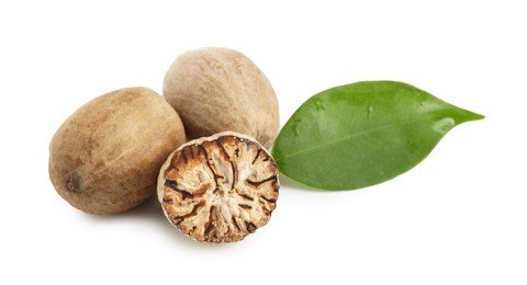 Photo of Whole, cut nutmegs and leaf isolated on white
