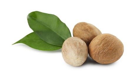 Photo of Whole nutmegs and leaves isolated on white