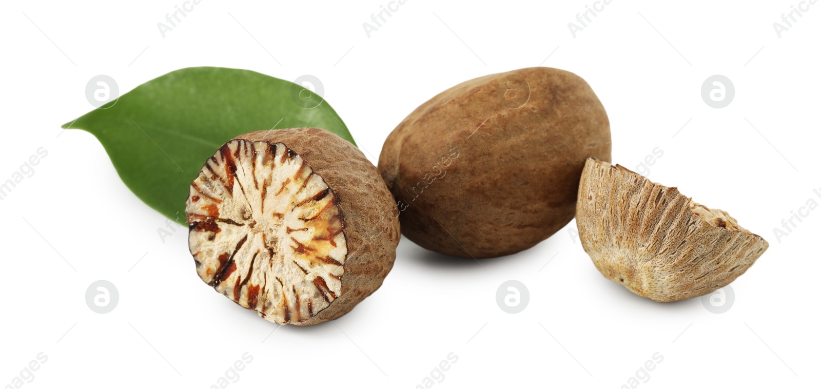 Whole, cut nutmegs and leaf isolated on white Photo of Whole, cut nutmegs and leaf isolated on white