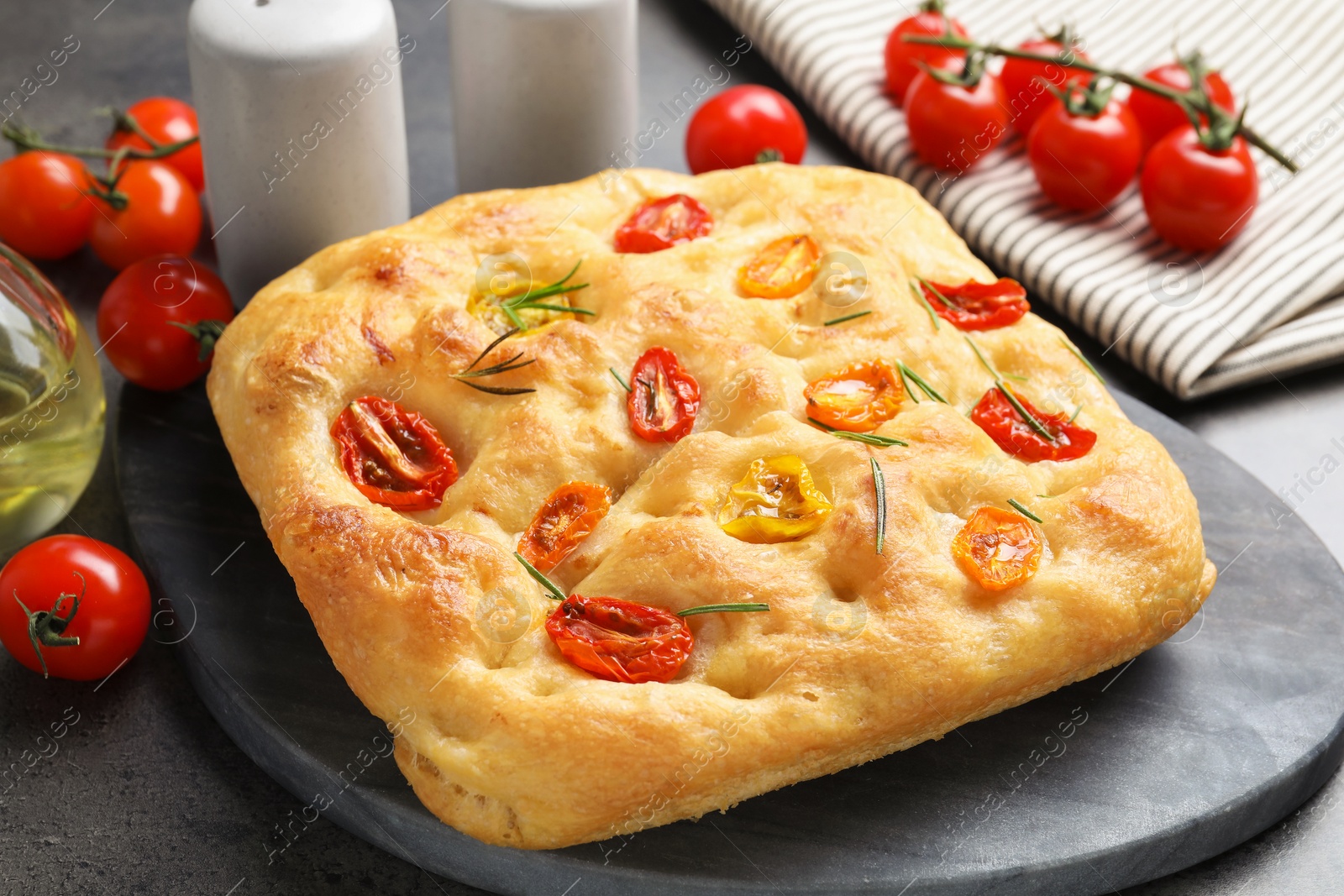 Delicious focaccia with tomatoes and rosemary on gray table, closeup Photo of Delicious focaccia with tomatoes and rosemary on gray table, closeup