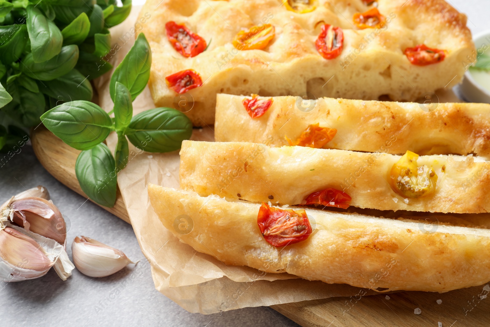 Cut delicious focaccia with tomatoes and spices on gray table, closeup Photo of Cut delicious focaccia with tomatoes and spices on gray table, closeup