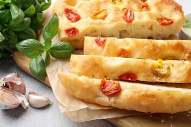 Photo of Cut delicious focaccia with tomatoes and spices on gray table, closeup