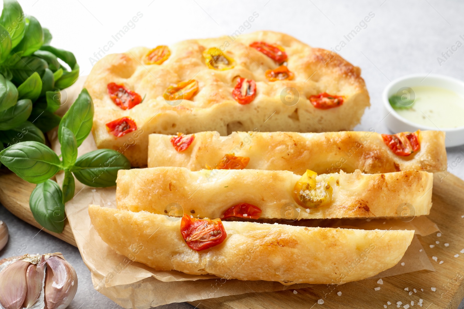 Cut delicious focaccia with tomatoes, spices and oil on gray table, closeup Photo of Cut delicious focaccia with tomatoes, spices and oil on gray table, closeup
