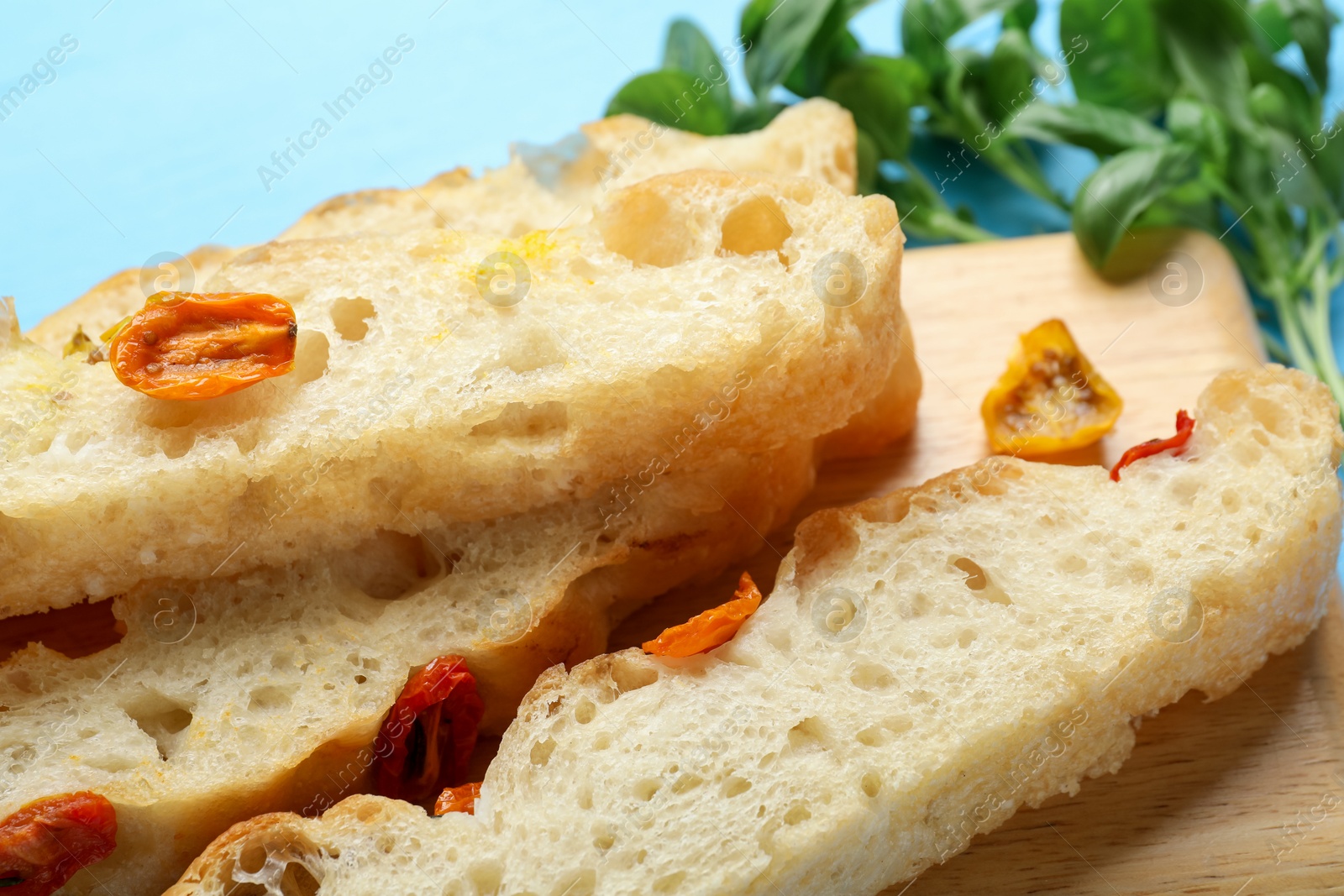 Pieces of delicious focaccia with tomatoes and basil on light blue table, closeup Photo of Pieces of delicious focaccia with tomatoes and basil on light blue table, closeup