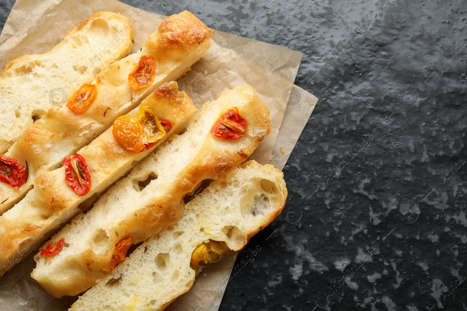 Pieces of delicious focaccia with tomatoes on dark textured table, top view. Space for text Photo of Pieces of delicious focaccia with tomatoes on dark textured table, top view. Space for text