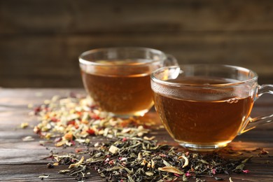 Photo of Refreshing herbal tea and dry leaves on wooden table, closeup