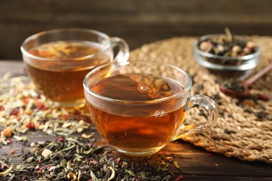 Photo of Refreshing herbal tea and dry leaves on wooden table, closeup