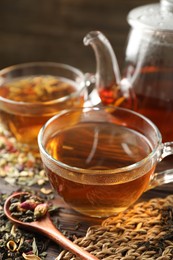 Photo of Refreshing herbal tea and dry leaves on wooden table, closeup