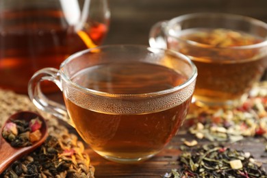 Photo of Refreshing herbal tea and dry leaves on wooden table, closeup