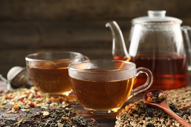 Photo of Refreshing herbal tea and dry leaves on wooden table, closeup. Space for text