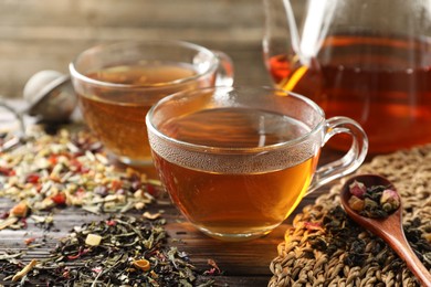 Photo of Refreshing herbal tea and dry leaves on wooden table, closeup