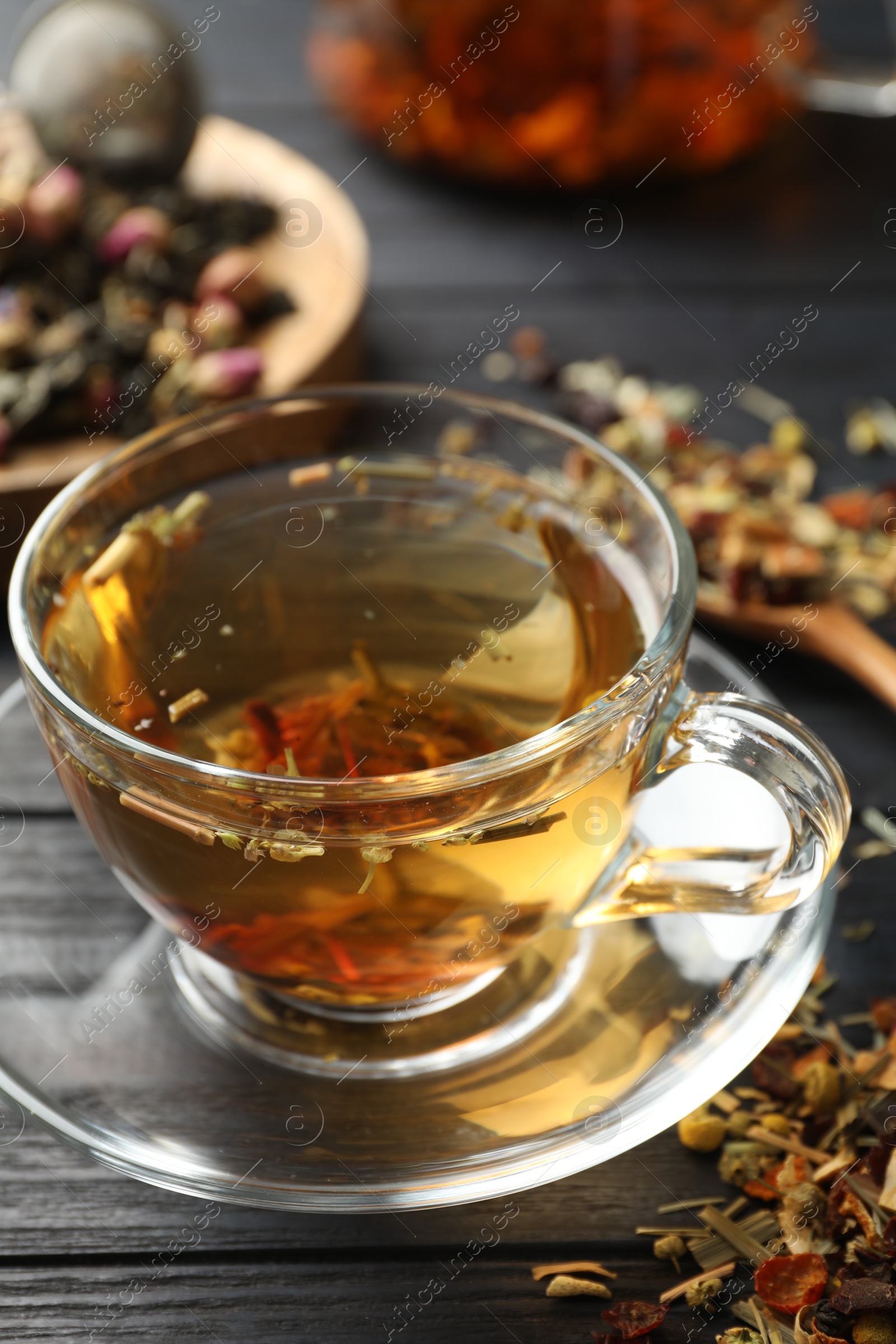 Refreshing herbal tea and dry leaves on black wooden table, closeup Photo of Refreshing herbal tea and dry leaves on black wooden table, closeup