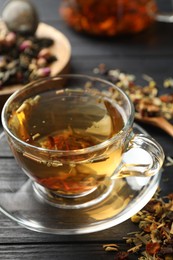 Photo of Refreshing herbal tea and dry leaves on black wooden table, closeup