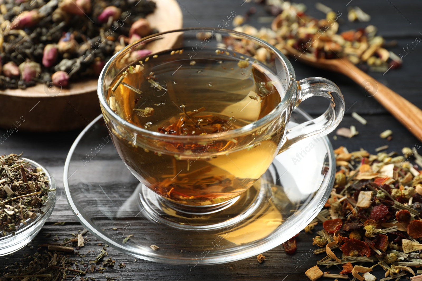 Refreshing herbal tea and dry leaves on black wooden table, closeup Photo of Refreshing herbal tea and dry leaves on black wooden table, closeup
