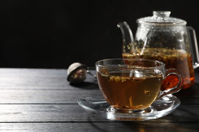 Photo of Refreshing herbal tea on black wooden table, closeup. Space for text