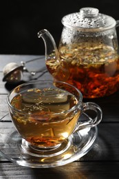 Photo of Refreshing herbal tea on black wooden table, closeup