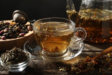Photo of Refreshing herbal tea and dry leaves on wooden table, closeup