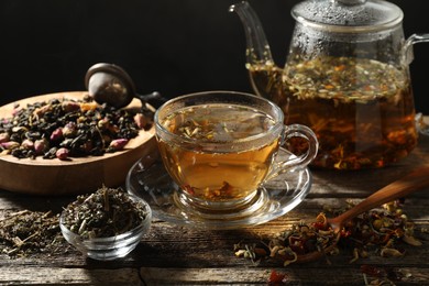 Photo of Refreshing herbal tea and dry leaves on wooden table, closeup