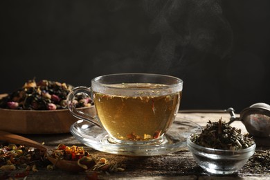 Photo of Refreshing herbal tea and dry leaves on wooden table, closeup. Space for text
