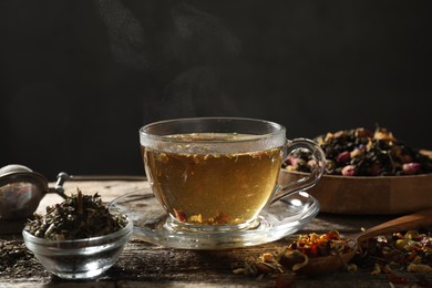 Photo of Refreshing herbal tea and dry leaves on wooden table, closeup. Space for text