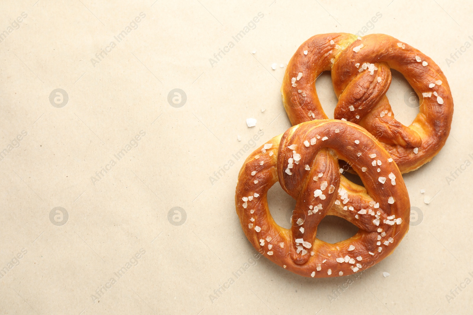 Tasty pretzels with salt on beige background, flat lay. Space for text Photo of Tasty pretzels with salt on beige background, flat lay. Space for text